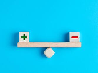 wooden blocks with plus and minus symbols balance on scale